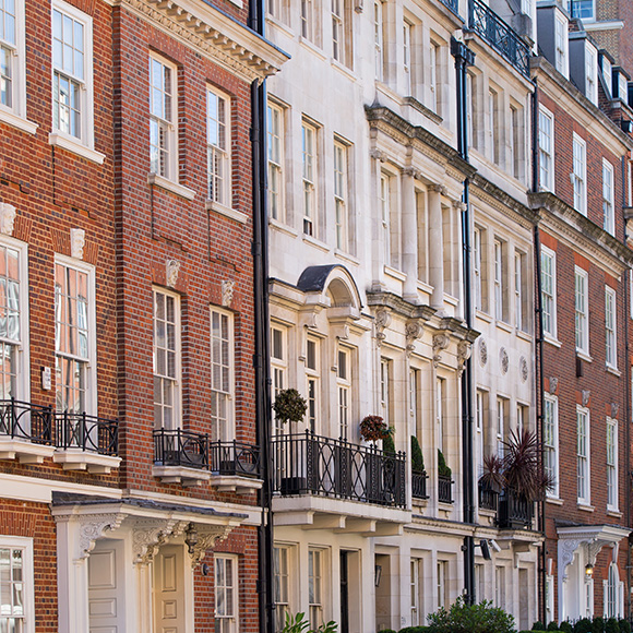 row of elegant residential buildings featuring red brick and white stone facades with balconies and windows showcasing classic architecture in an urban setting depicting two distinct styles of design